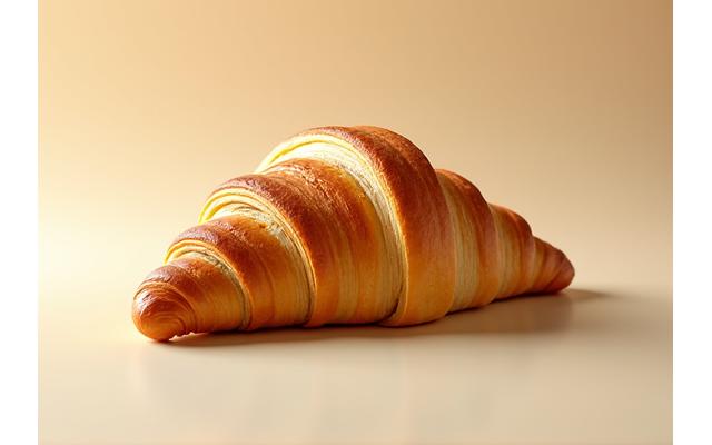 Croissant doré et feuilleté parfait sur un fond clair